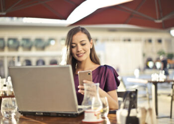 Woman wearing purple shirt holding smartphone white sitting on chair
