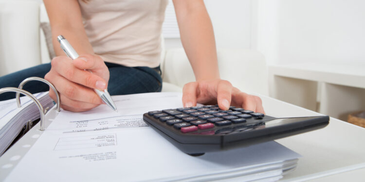Woman Calculating Home Finances At Table
