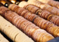 Hungarian chimney cake – the emblematic sweet of Hungary 2 Budapest is always filled with the delicious aroma of chimney cake, a favorite treat throughout the year and especially beloved during the winter. This pastry is a highlight at Christmas markets in the city, known for its irresistible sweetness and best enjoyed warm, straight from the oven. Trying a chimney cake Budapest offers not just a delightful snack but a memorable experience. This cherished pastry, hailing from Transylvania, is usually coated with sugar and spices like cinnamon, vanilla, cocoa, or nuts. However, many stalls in Budapest have put their own twist on the classic, offering innovative versions such as chimney cakes shaped like cones and filled with ice cream or Nutella, or even split in half and topped with sweet or savory ingredients. Prepare your taste buds for an exciting journey through the world of chimney cake Budapest! Hungarian chimney cake – the origin of this fine dessert Chimney cakes, known as kürtőskalács in Hungary, are named for their chimney-like appearance, featuring a crispy exterior and a soft, sweet interior. They are traditionally made from a sweet dough that's wrapped around a spit and cooked over charcoal until it turns golden-brown, with the sugar-coating caramelizing to perfection. However, chimney cakes weren't always a sweet treat. This pastry, often hailed as one of Hungary's oldest, was first mentioned in a German document during the Middle Ages. By the 15th century, it was described as dough that was rolled out, then cooked on a rotating spit to form its distinctive spiral shape. Chimney cakes have evolved significantly over time, taking on various shapes and flavors across Central and Eastern Europe, known as 'trdelnik' in Slovakia and 'trdo' in the Czech Republic. Originating from Transylvania, the earliest known recipe for chimney cake dates back to 1784 and initially didn't include any sweeteners. The addition of sugar and almond coatings came later. Chimney cake Budapest – the best places to try this sweet pleasure in the city Now that you're familiar with the background of chimney cakes, it's time to try some for yourself. Budapest has many wonderful cafés and stands offering delicious chimney cakes in a variety of shapes, sizes, and flavors. First, though, it's a good idea to begin with the traditional versions. Kurtos kalacs chimney cake: Molnár’s Kürtőskalács Café Molnár’s Café is a top choice for cake lovers on Váci Street. When you're in the mood for something sweet while exploring Váci Street, Budapest's main shopping area, make your way to Molnár’s Kürtőskalács Café near Fővám tér. Offering both indoor and outdoor seating, this café provides eight delicious flavors of chimney cakes throughout the entire year. Once you try a chimney cake here, you'll definitely want to return for another taste of this delightful Hungarian specialty! One of the best kürtőskalács in the city at Vitéz Kürtős’ When you're near Városliget (City Park), Széchenyi Bath, or the Budapest Zoo, make sure to stop by Vitéz Kürtős' Sweet Bear chimney cake shop. Alongside traditional toppings, they offer unique fruity options such as raspberry, strawberry, and blueberry for an extra special treat. Discover unique chimney cakes in Budapest – a memorable street food experience. We've touched on some unique versions of chimney cakes, such as those stuffed with ice cream or made in vibrant colors, but there's much more to explore. Massage Budapest – another way of relaxation Dive into the ultimate relaxation experience in Budapest, where you're invited to indulge in unparalleled massage therapies. Budapest presents the finest selection of massages from across the globe, designed to rejuvenate both mind and body, ensuring a state of perfect tranquility. Budapest, a city bursting with endless delights, offers more than just its famed thermal baths and exciting water parks for those seeking aquatic adventures. Explore the vibrant nightlife, from iconic ruin pubs to chic rooftop bars and pulsating techno clubs. For those with a keen interest in culture, the city doesn't disappoint, with its rich historical landmarks, stunning vistas, and cultural institutions offering a feast for the intellect. After a day filled with such diverse activities, or simply to take a well-deserved break, pamper yourself at one of the capital's premier massage establishments. In Budapest, massage experiences are diverse, grouped into four main categories to cater to every preference for those in search of the perfect massage within the heart of Hungary. If you are interested in special treatments like sensual massage Budapest - this article is for you. We'll introduce you to the most sensual, pampering salons where you're sure not to leave unsatisfied. Massage Budapest – what choices do we have? So, about the 4 categories mentioned above: Massage offerings in Budapest's wellness spots: The variety of massage treatments available in Budapest's baths is impressive, covering everything from aromatic and rejuvenating massages to the classic Swedish and deep tissue techniques. Guests can also opt for specialized treatments like the gentle Breuss massage or targeted cellulite reduction therapies. Exploring Thai massage in Budapest: The city's landscape is dotted with numerous Thai massage centers, particularly noticeable around the central districts. This prevalence highlights a unique aspect of Budapest's wellness culture, with many of these centers offering easy-to-book sessions that cater to both spontaneous and planned visits. Cultural massage experiences in Budapest, Hungary: Among the massage options, there are treatments deeply embedded in cultural practices, including traditional Indian and Hungarian techniques. While predominantly found in Budapest, these authentic experiences are also accessible in smaller towns and are a staple in some boutique bathhouses. Specialized erotic massage Budapest: A segment of the Budapest massage market is dedicated to providing services primarily for a male audience, with some establishments specializing in erotic massages. Notably, even within some Thai massage parlors in the city, there exists the provision for massages with a 'happy ending', catering to those seeking an adult-oriented relaxation experience. About Rudas Baths, Gellért Baths, Lukács Baths and Széchenyi Baths At the Rudas Baths, uniquely home to Budapest's sole outdoor panoramic pool, a variety of massages are offered to visitors. Access to these indulgent treatments requires the acquisition of an entry pass, priced at 25 euros during the week and 32 euros for weekend visits. Meanwhile, the Gellért Baths stand out as one of Hungary's most stunning thermal bath complexes, where guests can choose from an array of massages, including aromatic options. Entry to this exquisite facility, and thereby access to its massage services, necessitates the purchase of an admission ticket, costing 28 euros on weekdays and 32 euros on weekends. Over at the Lukács Baths, visitors can find some of the most affordably priced massages in Budapest. To partake in these services, one must first buy a bath entry ticket, which is available at 13 euros on weekdays and 14 euros on weekends, making it an attractive option for budget-conscious visitors. Trdelnik - grilled rolled dough, Czech hot sweet pastry